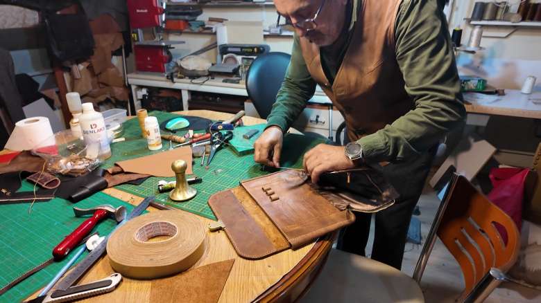 Craftsman hand-stitching leather in a workshop